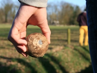 Wachtend op zijn beurt kijkt de klootschieter toe hoe het andere team hun beurt benut. Met de mooie omgeving van Klimpark Streekbos.